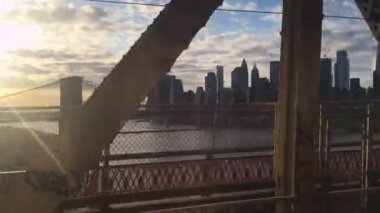 Manhattan ve Brooklyn Köprüsü 'nün gün batımındaki görüntüsü, şehir merkezindeki köprüden Doğu Nehri' ni geçerken metro penceresinden gelen metal kirişlerle kesişiyordu.