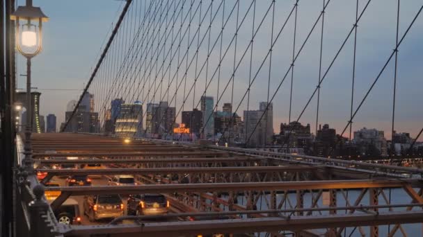 黄昏时分 布鲁克林大桥上的摩天大楼和灯光映照在人行横道上 汽车沿着桥行驶 — 图库视频影像