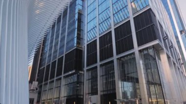 New York Ocak 2020 - New York 'taki Oculus binasının yanındaki gökdelenin mavi cam cephesinin düşük perspektifi. Önplanda Oculus 'un beyaz bir kanadının beyaz yapısı. yukarı eğ