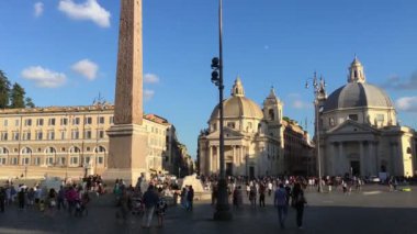 Roma - Eylül 2019 - Roma 'daki Piazza del Popolo' da antik yazıtlarla süslenmiş dikilitaşın yanında yürüyen ve eğlenen insanlar, sağa doğru hareket eden kameralar