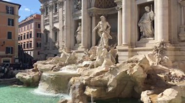 Roma - Eylül 2019 - Trevi Çeşmesi 'ni çerçeveleyen kameranın küçük bir hareketi yaz gününün güneşiyle aydınlatılan arka planda insanlarla dolu bir sokak
