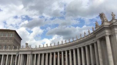Kameranın sağındaki panoramik hareket, San Pietro Bazilikası 'nın sağ sütununun başlangıcını ve bulutlu bir günde atari salonunun tepesinde duran heykellerini yavaşça gözler önüne seriyor.