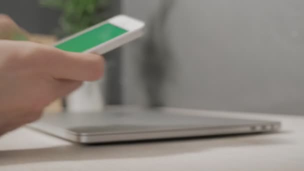 ミラノ 2019年12月 男の手は机から緑色の画面で彼のリンゴのスマートフォンを取り それを彼の本のプロの隣に置きます — ストック動画