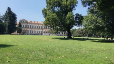 Monza, Ağustos 2019. Turistler yaz günü Monza Kraliyet Sarayı 'nın parkında güneşlenirler. Kamera sağa kaydır