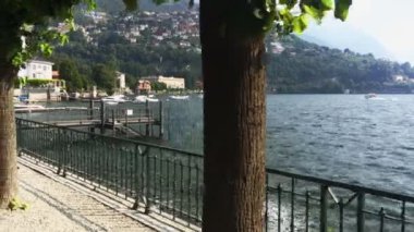 Cernobbio, Temmuz 2019. Göl kenarındaki ağaçlık caddede, rıhtımın ve köy kilisesinin manzarasında çekim yapılıyor.