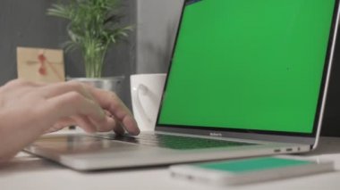 Milan, Aralık 2019 - M yeşil ekranlı bir Macintosh dizüstü bilgisayarı üzerinde çalışıyor, telefonuna yeşil ekran ile cevap veriyor, sonra da Macintosh Macintosh 'un ekranını kapatıyor.