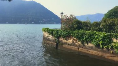 Cernobbio köyündeki Como Gölü kıyısında tuğladan bir duvar ve yemyeşil bir bahçe.