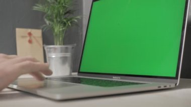 Milan, Aralık, 2019 - Bir adamın eli zoom yapıyor ve yeşil ekranlı bir dizüstü bilgisayarın iz sürme hareketini yapıyor bir mektup ve bir bitkiyle birlikte beyaz bir masaya yaslanıyor