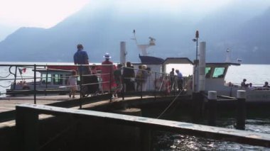 Cernobbio, Temmuz 2019 - turistler yaz günü Como Gölü 'ndeki ahşap köprüden feribota binerler.