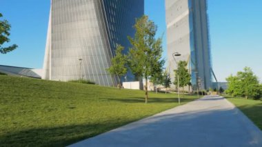 Milano 'nun Citylife semtindeki küçük bir yolun zemin perspektifinden kamera hareketleri ve güneşli bir günde arka planda modern gökdelenler. Kamera yukarı.