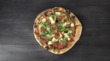 Siyah ahşap masa üzerinde taze pişmiş pizza döndürme, üst görünüm, 4k