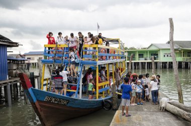 Malezya 'nın Pulau Ketam kentindeki iskeledeki ahşap tekneyi turlayan kimliği belirsiz turistler görülüyor.