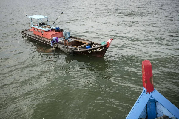 身份不明的渔民正在把渔网从海上拖到马来西亚普劳凯塔姆的渔船上 — 图库照片