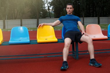 Stadyumbankında oturan yakışıklı sporcu. Rahatlatıcı