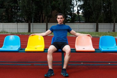 Stadyumbankında oturan yakışıklı sporcu. Rahatlatıcı