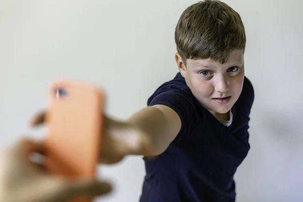 Blond fat kid reaches his hand to the mobile phone. Phone addiction concept