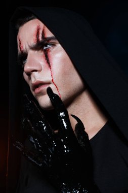 Necromancer kanlı yaralar ile siyah kapüşonlu ayakta ve ileriye bakıyor