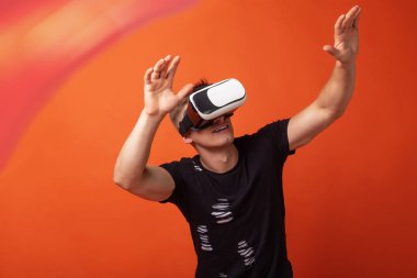 Turuncu stüdyo arka planda kafasında bir kulaklık ile sanal gerçeklik genç adam