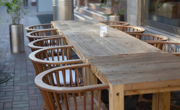Long wooden table and chairs for big company reserved on the street summer restaurant terrace