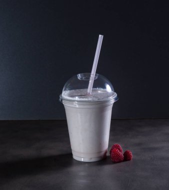 İçecek tüpü ve ahududu ile koyu arka plan üzerinde bir milkshake