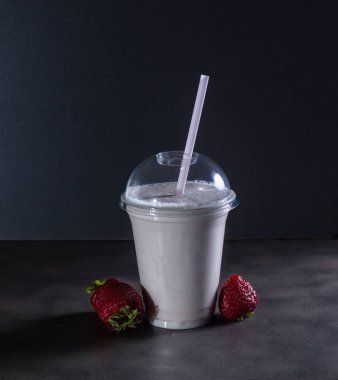 İçecek tüp ve çilek ile koyu arka plan üzerinde bir milkshake