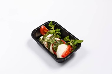 Mozzarella ve siyah tepside beyaz bir arka plan üzerinde otlar ve yeşillik ile domates. Üstüne lahana ile Pesto sosu. Sağlıklı gıda kavramı izole