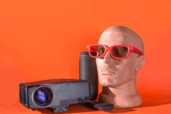 Home Theater concept. Projector with remote control, bluetooth speaker, 3d glasses on mannequin