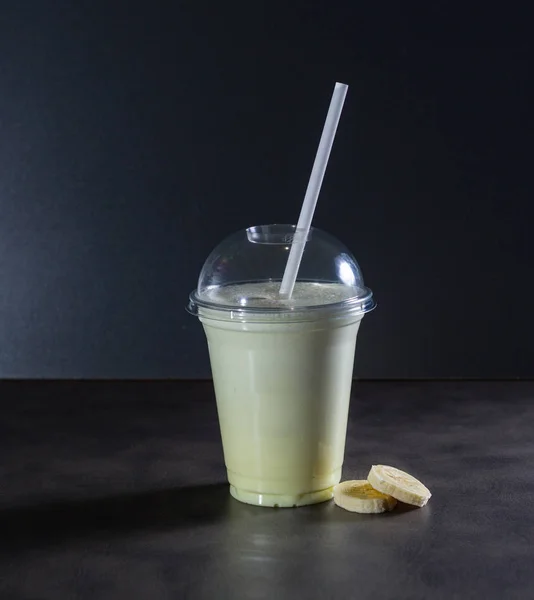 İçecek tüp ve muz ile karanlık arka plan üzerinde bir milkshake