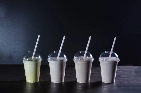 İçecek tüpleri ile karanlık arka planda dört farklı milkshakes