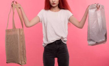 Elinde iki çanta tutan yüzü olmayan bir kız. Çevre dostu ve arka planda plastik.