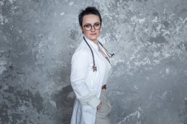 Gri arka planda şık bir doktor kadın.
