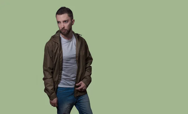 young man in clothes stands on a green background Blank for the designer. Place for text