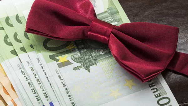 kahverengi bir not defteri arka plan ve kırmızı papyon üzerinde bir zarf içinde para