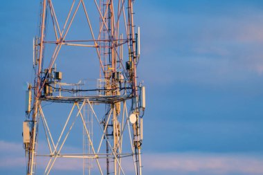 5g mobil iletişim kulesi mavi bulutların arka planında caddede duruyor.