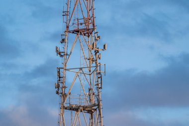 5g mobil iletişim kulesi mavi bulutların arka planında caddede duruyor.