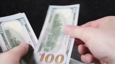 Beyaz tenli adam elleriyle dolarları sayıyor.