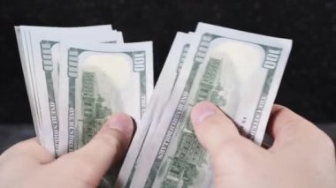 Beyaz tenli adam elleriyle dolarları sayıyor.