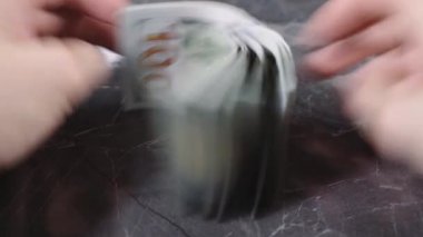 Beyaz tenli adam elleriyle dolarları sayıyor.