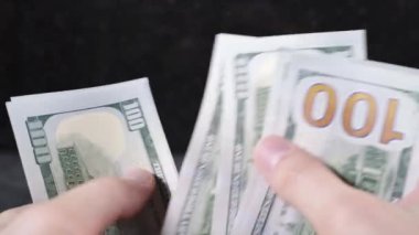 Beyaz tenli adam elleriyle dolarları sayıyor.