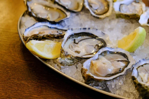 Placa de ostras con limón sobre fondo marrón. Mesa servida con ostras y limón . —  Fotos de Stock