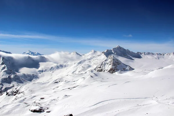 Zasněžené hory v oblacích modrá obloha Kavkazu Elbrus — Stock fotografie