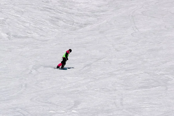 Dziewczyna w kolorowy komplet jest na desce snowboardowej jeździ z góry — Zdjęcie stockowe