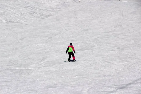 Dziewczyna w kolorowy komplet jest na desce snowboardowej jeździ z góry — Zdjęcie stockowe