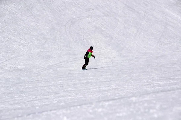 Dziewczyna w kolorowy komplet jest na desce snowboardowej jeździ z góry — Zdjęcie stockowe