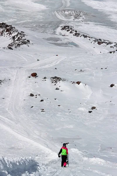 Chica en un traje de colores con una tabla de snowboard está en el camino de la montaña — Foto de Stock