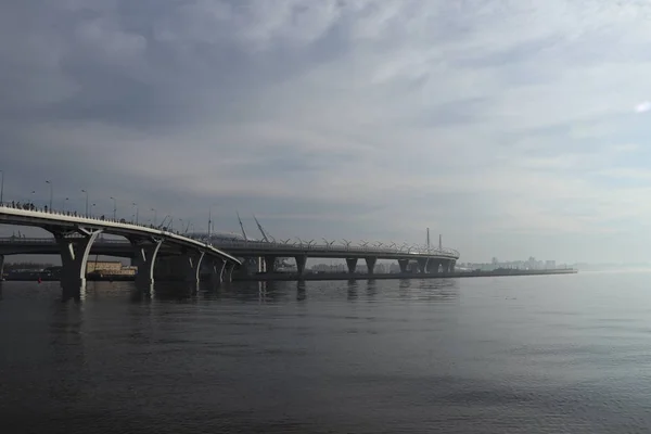Sis fütüristik görünümü ile geniş nehir üzerinde iki dolambaçlı otoyol köprüler — Stok fotoğraf