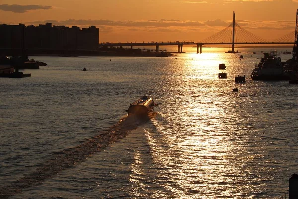 Nehir üzerinde turuncu gün batımı Köprü ve teknelerle