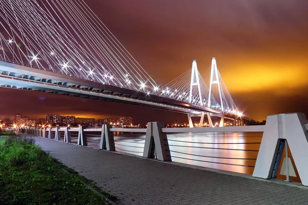 Grande ponte de cabo-permanecido sobre o rio à noite com iluminação brilhante colorida — Fotografia de Stock