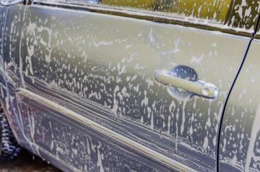 Mavi araba, araba yıkama dükkanında köpükle arabayı yıka..