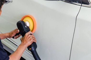 El ele tutuşan bir adam, araba kaputunu ve beyazı parlatan bir cilalama makinesi..